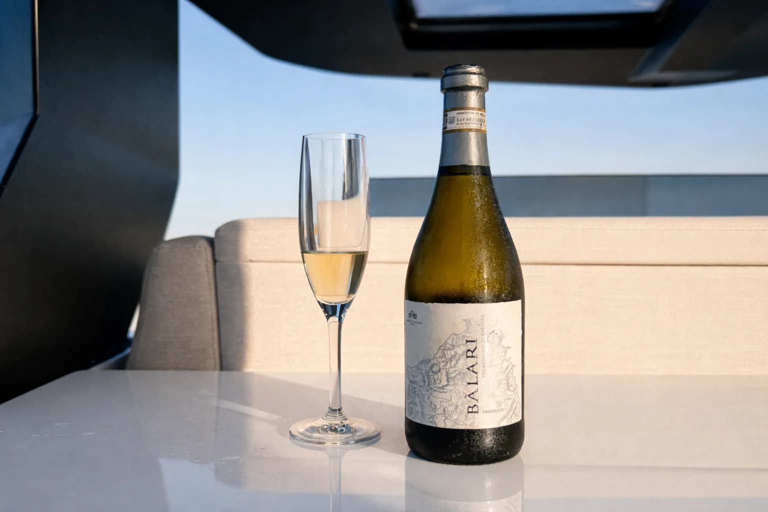 Calice di vino bianco sulla barca con la costa sarda