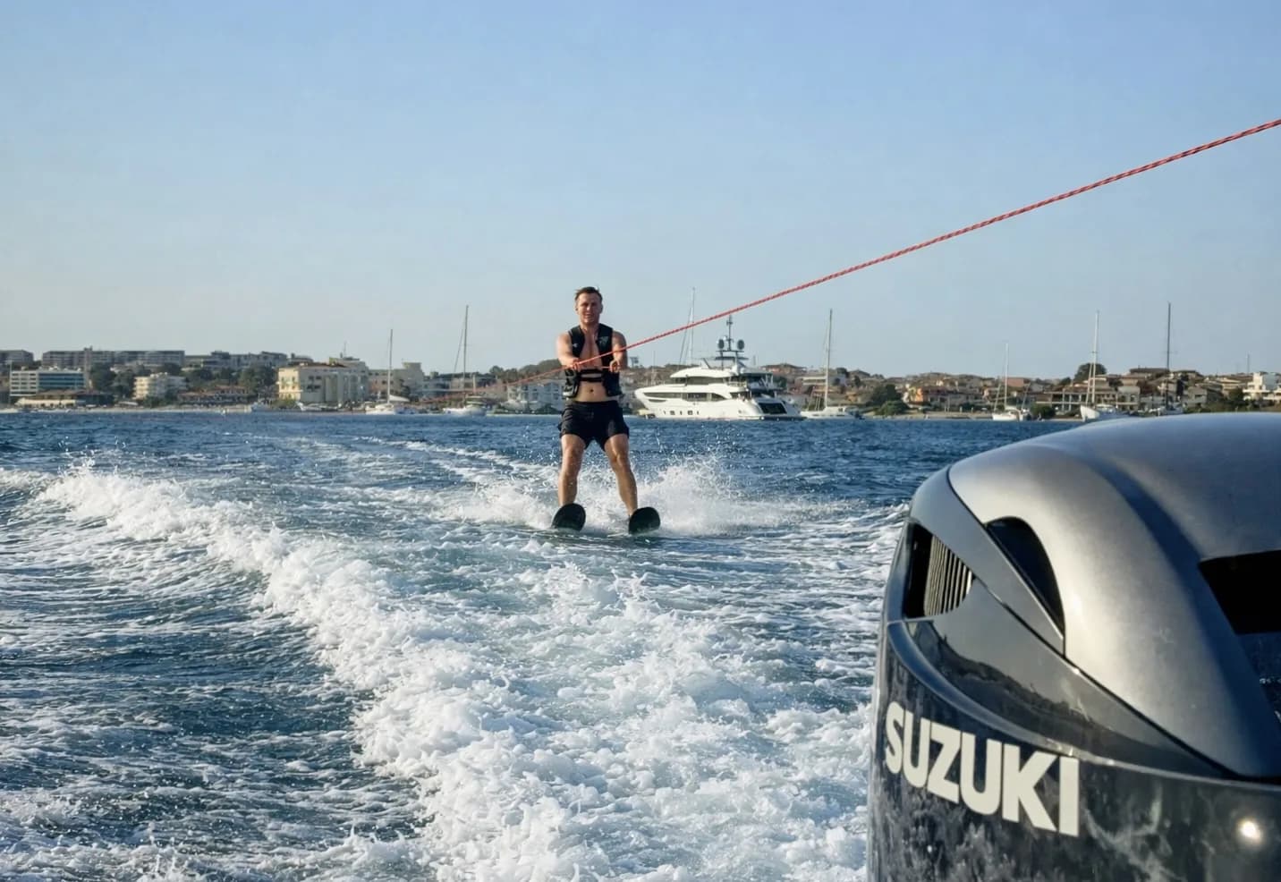 Mann fährt Wasserski hinter einem Boot mit Suzuki-Außenbordmotor in sardischen Gewässern