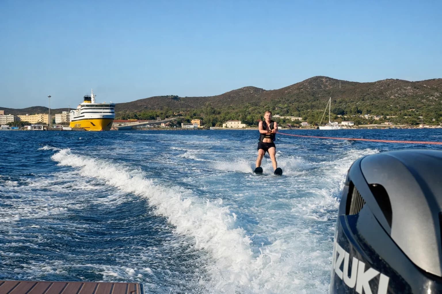 Luftaufnahme einer Charteryacht in türkisfarbener Bucht mit Wasserspielzeug im Wasser